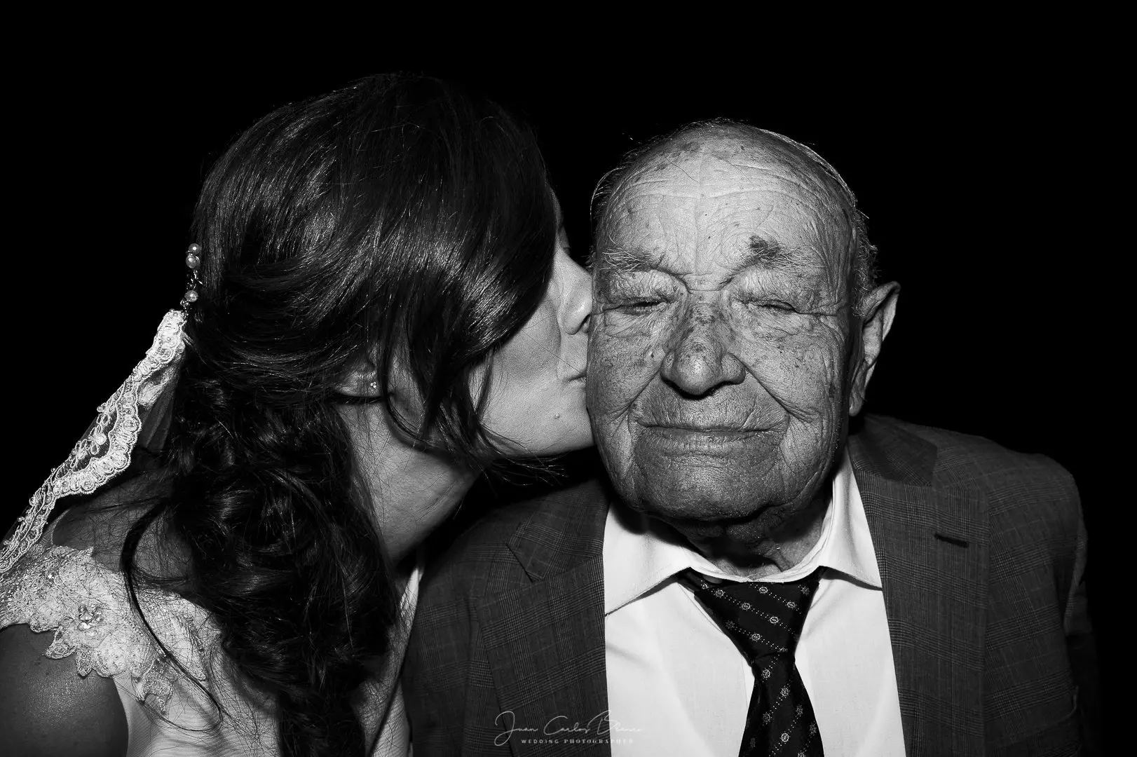La novia besa a su abuelo en el banquete, boda en blanco y negro