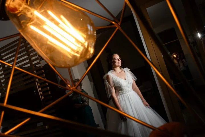 Retrato de la novia junto a una lámpara de bombilla en la boda de Elena y Enrique